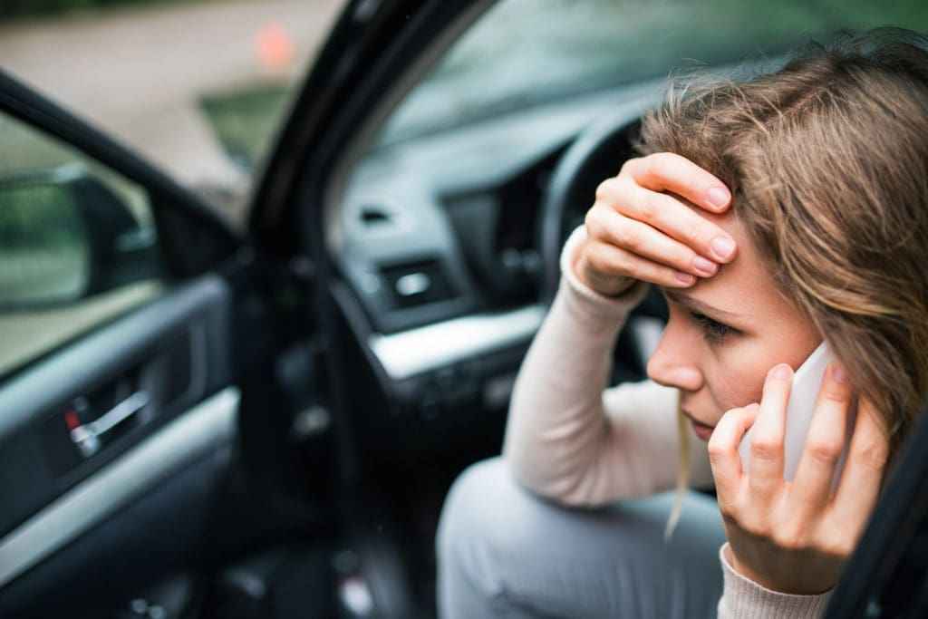 Distressed woman in car accident in Colorado, calling The McCrary Law Firm for personal injury representation. I Am Injured Colorado logo visible.